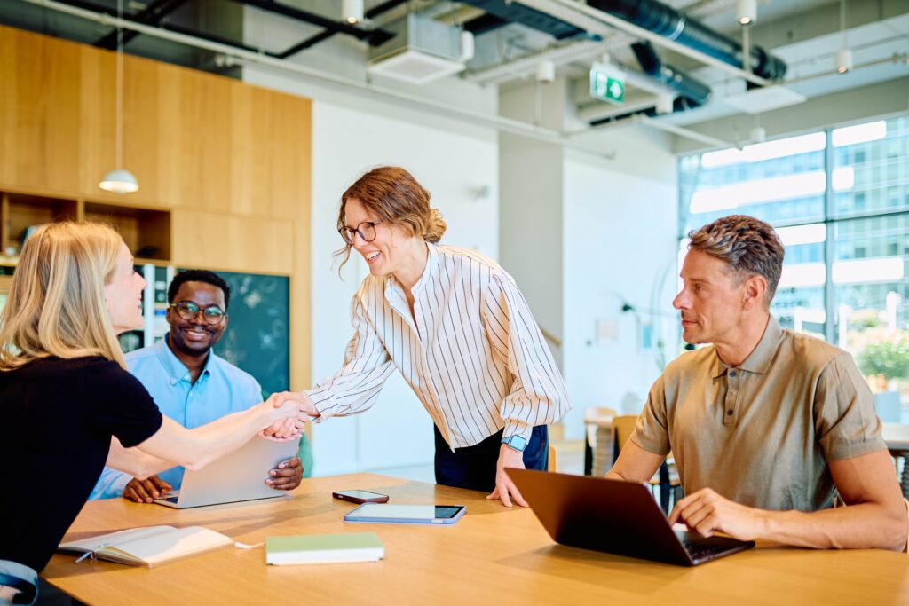 Consultants GPRH et clients autour d'une table, poignée de main lors d'une réunion d'externalisation RH